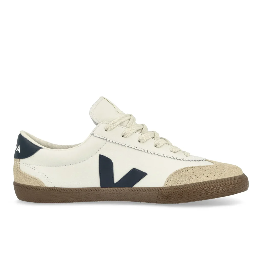Der Veja Volley O.T. Leather Weiss Schwarz Herren-Sneaker hat ein weißes Obermaterial aus Leder, beigefarbene Wildlederakzente, eine Gummisohle und ein schwarzes "V"-Logo an der Seite, das im Seitenprofil zu sehen ist.